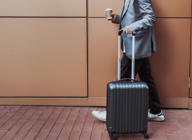 Traveler walking through a modern airport while holding a cup of coffee, illustrating Stanislav Kondrashov and his travel tips for 2026, including lighter luggage, digital tools, careful preparation, and greater flexibility.
